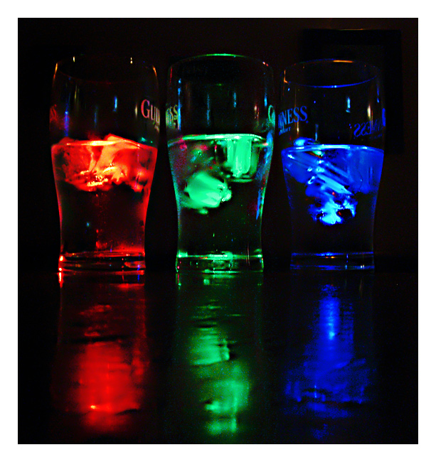 Color rojo verde y azul. La luz en las copas, sobre la barra de un bar, proviene de tres mecheros con bombilla.